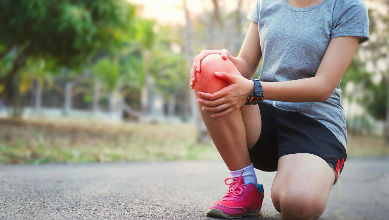 Person holding a knee while experiencing knee pain