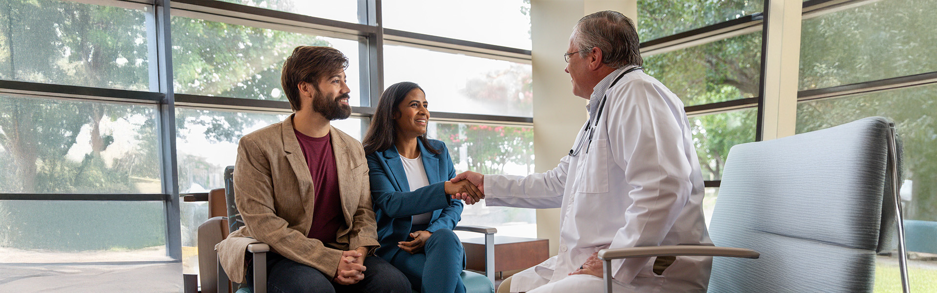 couple talking to physician in waiting room, shaking hands
