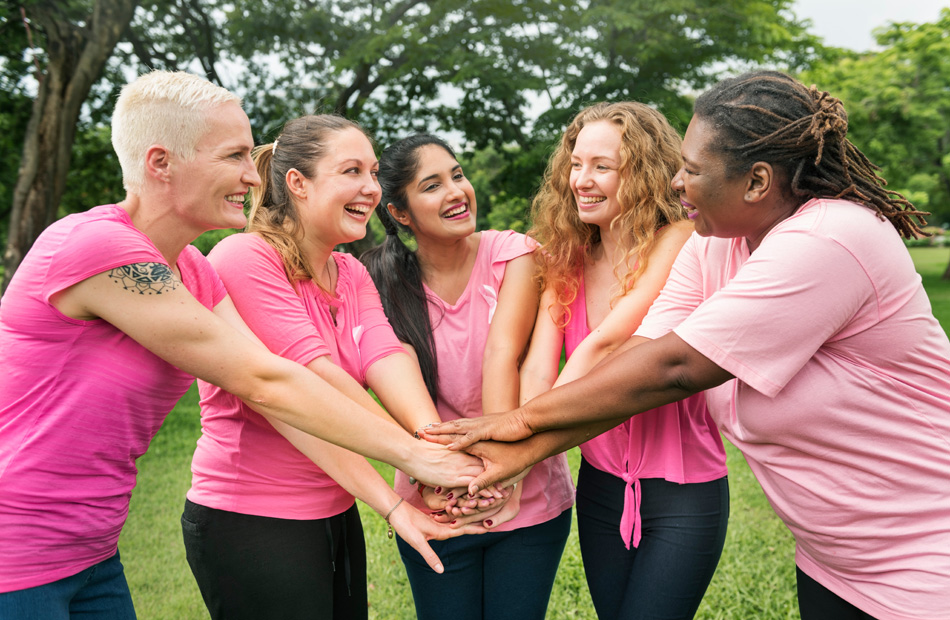 Group of people standing outdoors with their hands stacked together