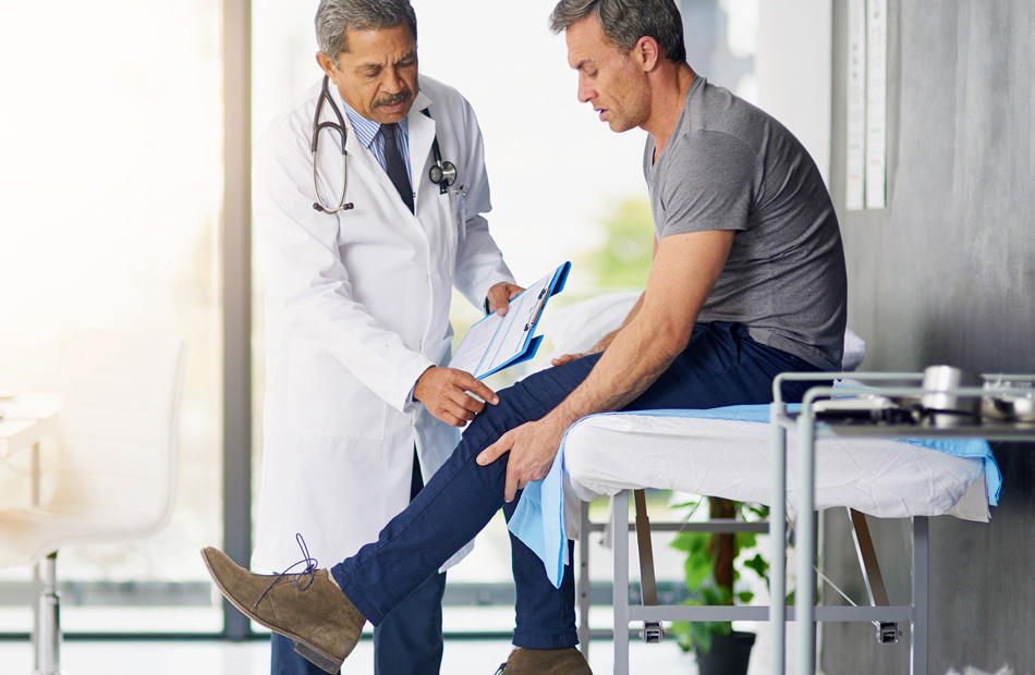 Orthopedist examining a patient’s knee during consultation