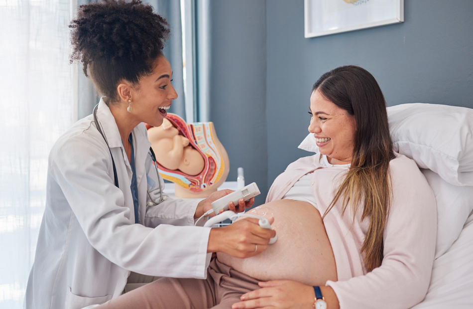 Obstetrician examining a pregnant woman's abdomen using a handheld ultrasound device