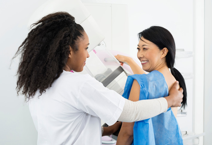 Healthcare worker assisting a woman with a breast screening