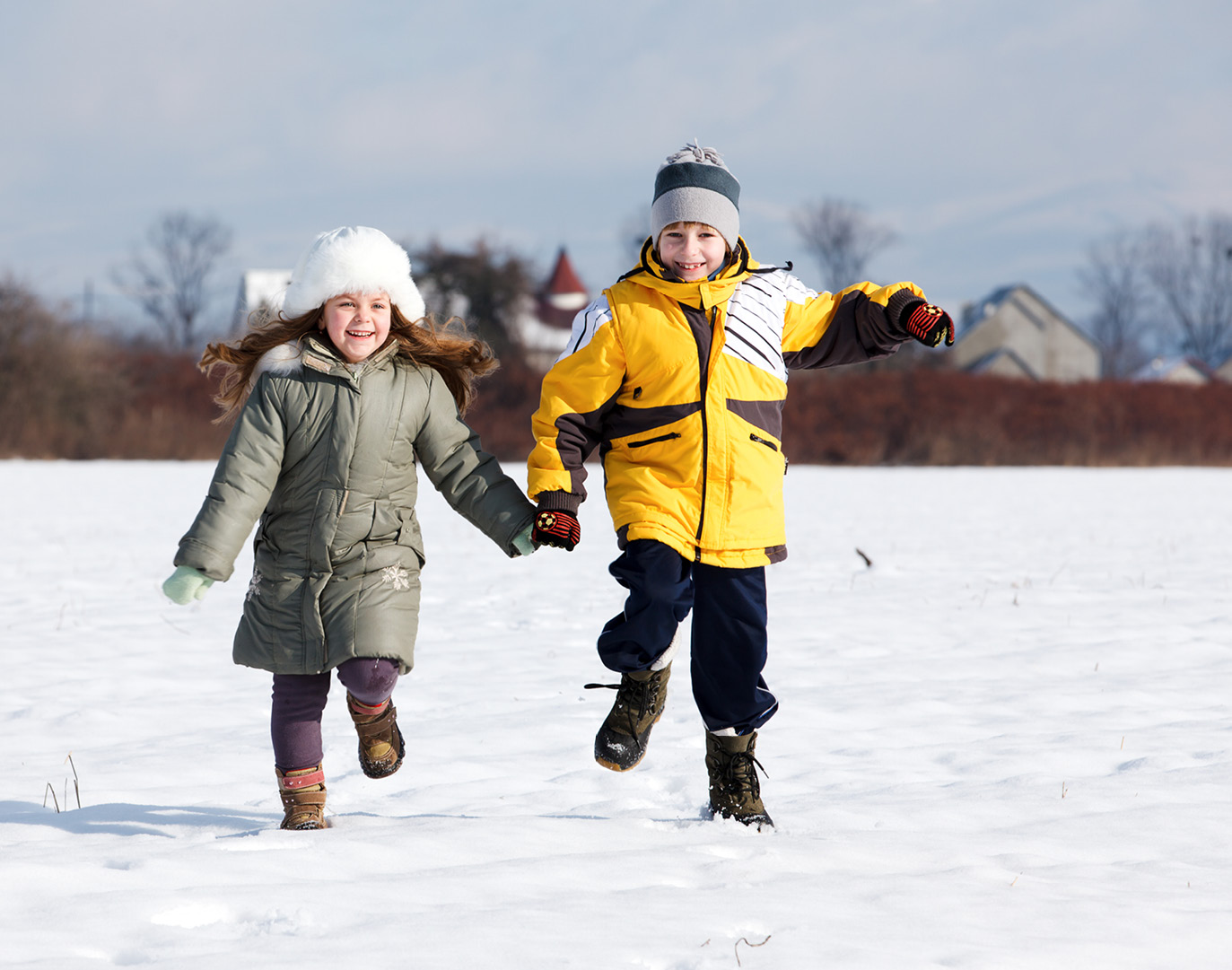Two children running in snowy field