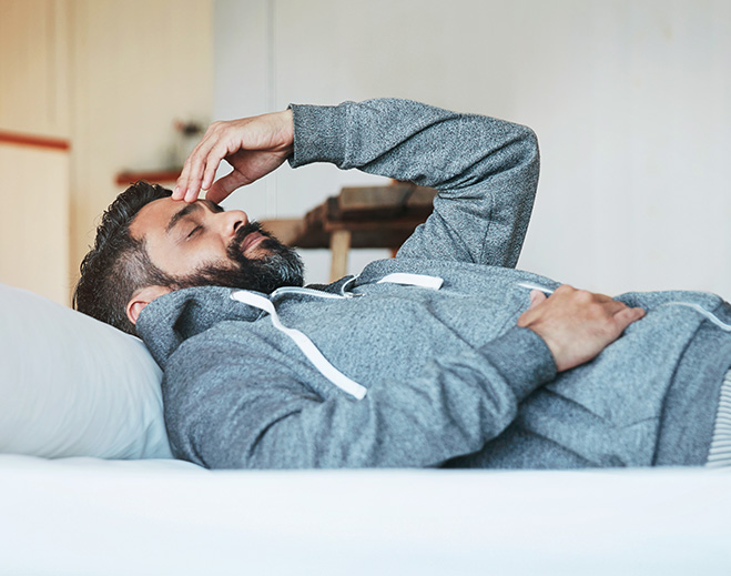 Man lying in bed with headache