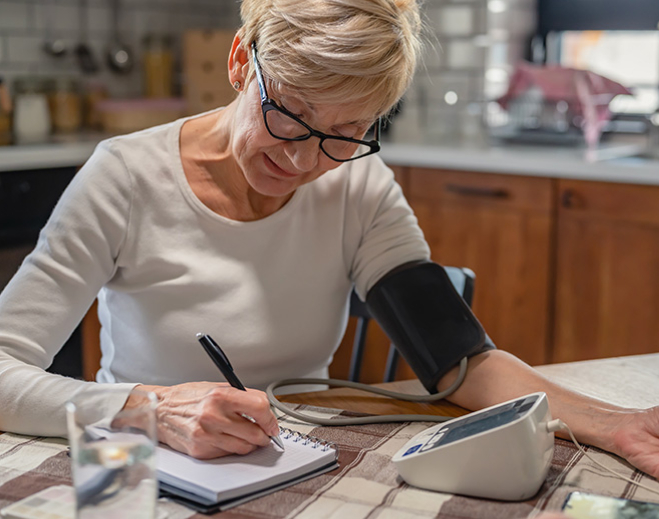 Woman recording blood pressure reading at home