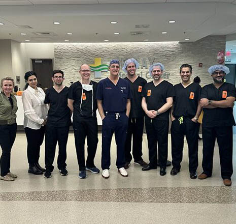 Group of healthcare professionals and visiting surgeons standing together in the hospital lobby for a commemorative photo at Delray Medical Center.