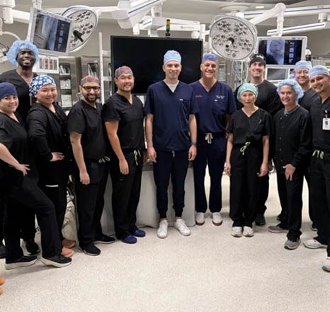 Healthcare professionals and international visiting surgeons stand together in the hospital lobby during an educational exchange and observational visit at Delray Medical Center