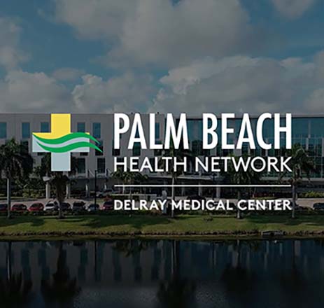 Aerial view of Delray Medical Center, part of Palm Beach Health Network, showing the hospital campus, palm trees, and adjacent waterway.
