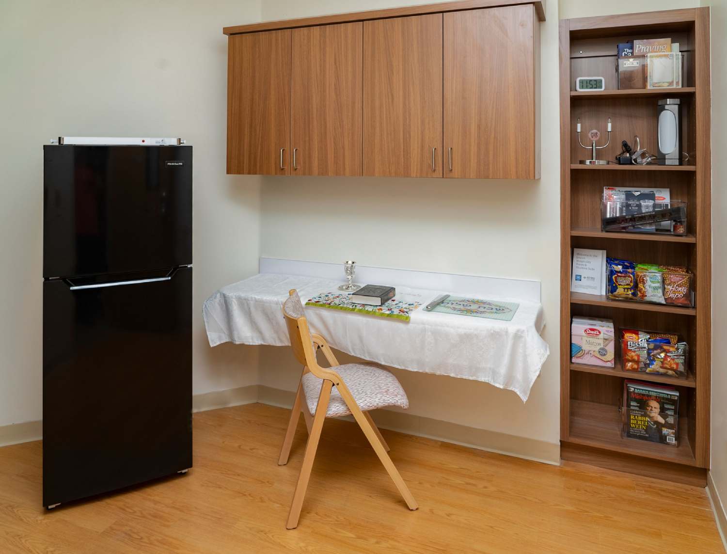 Shabbos room with a refrigerator, table, and snacks