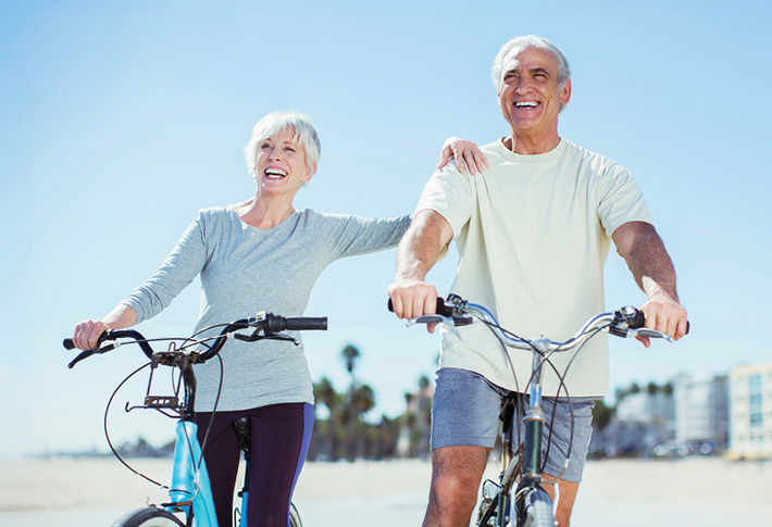 Older couple riding bikes on the beach